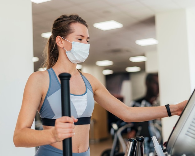 Photo gratuite femme exerçant dans la salle de gym avec masque