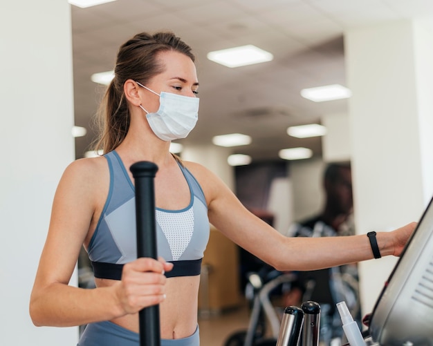 Femme exerçant dans la salle de gym avec masque