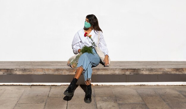 Femme à l'extérieur avec des fleurs et des sacs d'épicerie