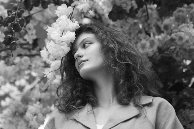 Photo gratuite femme à faible angle posant avec des fleurs en noir et blanc