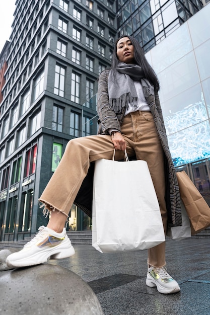 Femme de faible angle posant avec des sacs à provisions