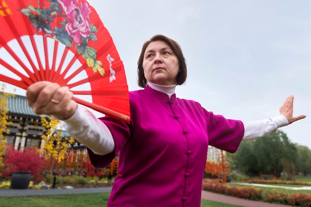 Femme à faible angle pratiquant le tai chi à l'extérieur