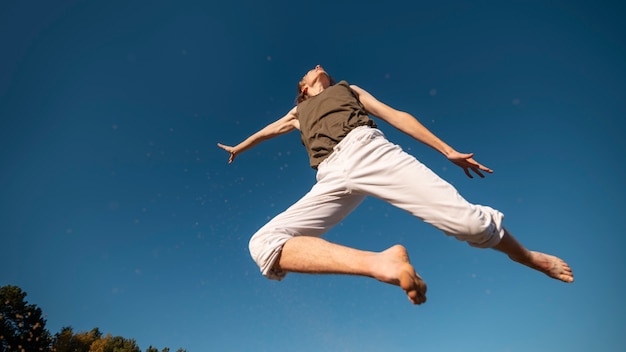 Photo gratuite femme à faible angle sautant dans la nature