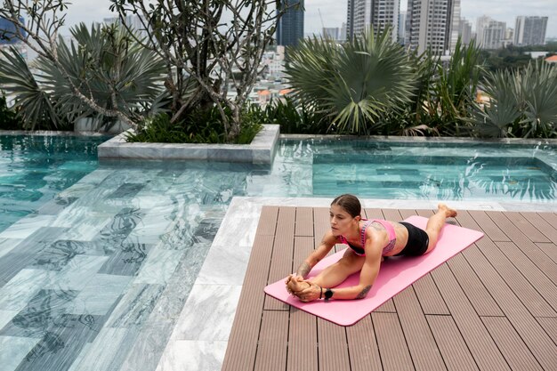 Femme faisant du yoga au bord de la piscine