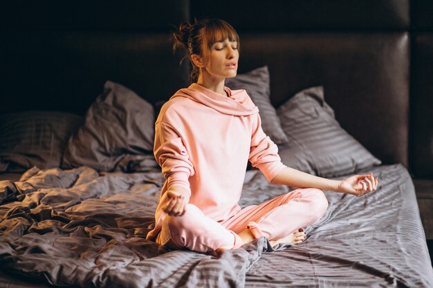 Femme faisant du yoga au lit