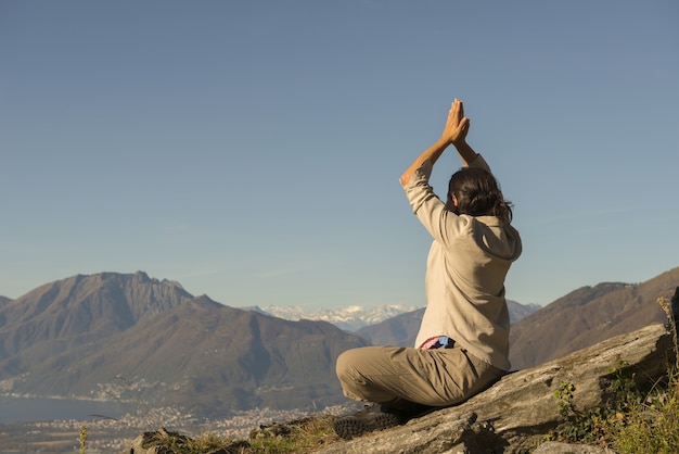 Femme faisant du yoga au sommet d'une montagne lors d'une journée ensoleillée en Suisse