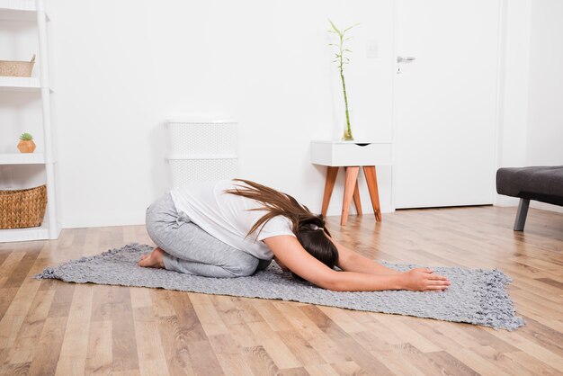 Femme faisant du yoga à la maison