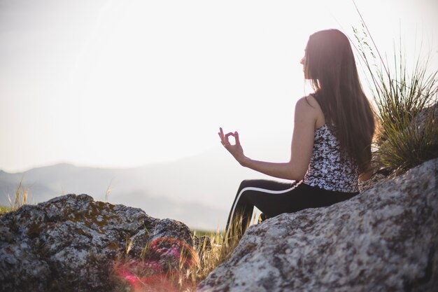 Femme faisant du yoga sur pierre