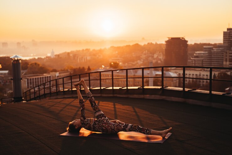Photo gratuit une femme faisant du yoga sur le toit d'un gratte-ciel dans une grande ville.