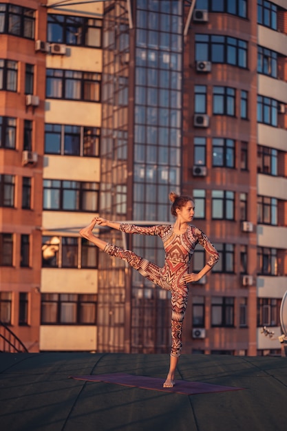 Photo gratuite femme faisant du yoga sur le toit d'un gratte-ciel dans la grande ville.