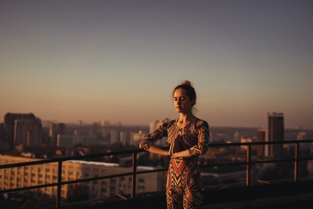 Femme faisant du yoga sur le toit d'un gratte-ciel dans la grande ville.