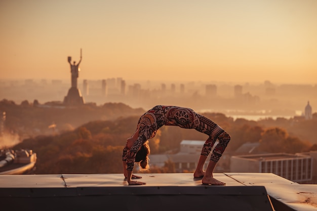 Femme faisant du yoga sur le toit d'un gratte-ciel dans la grande ville