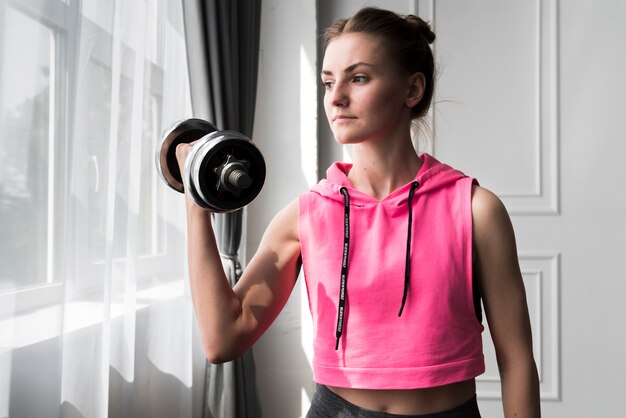 Femme faisant de l'exercice avec haltère à la maison