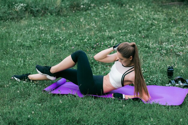 Femme faisant des exercices de force pour les muscles abdominaux au parc en plein air.