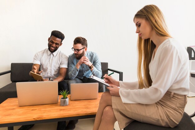 Femme faisant des notes près de collègues de travail