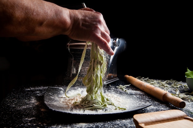 Femme faisant des pâtes en plaque avec des ustensiles de cuisine sur fond noir. vue latérale horizontale