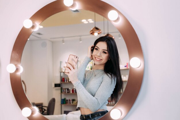 Femme fait selfie dans un miroir de maquillage avec lampes