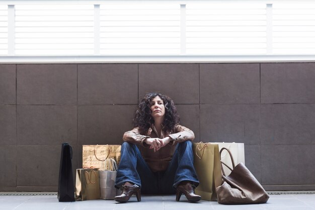 Femme fatiguée, assis avec des sacs à provisions sur la rue