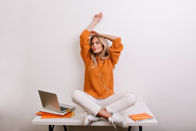 Femme fatiguée en baskets en cuir blanc qui s'étend après une dure journée, assis sur la table