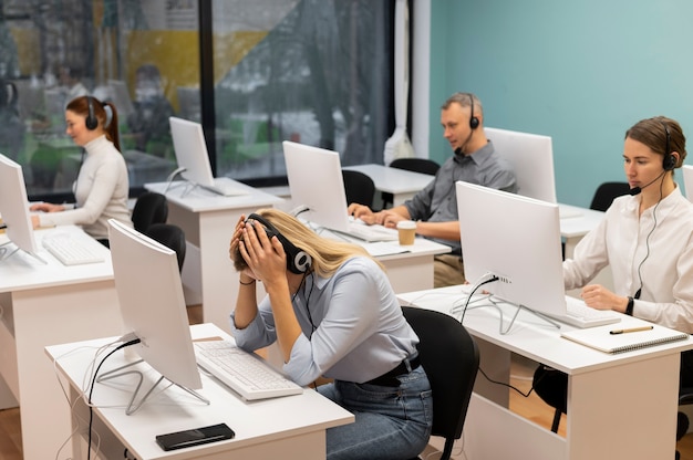 Femme fatiguée travaillant dans un bureau de centre d'appels entre collègues