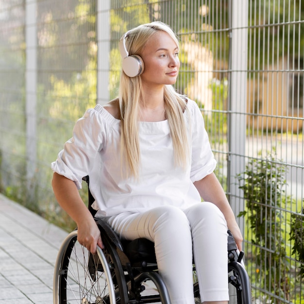 Femme en fauteuil roulant avec des écouteurs à l'extérieur