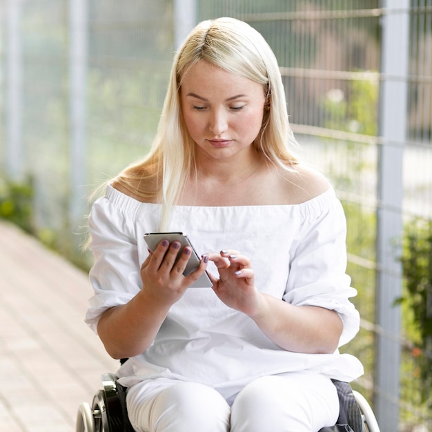 Photo gratuite femme en fauteuil roulant avec smartphone