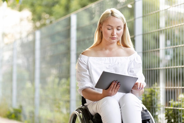 Femme en fauteuil roulant avec tablette