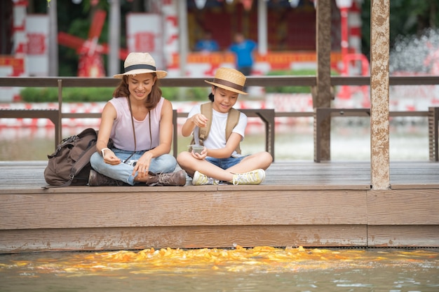 Photo gratuite femme et fille nourrir les poissons dans un étang