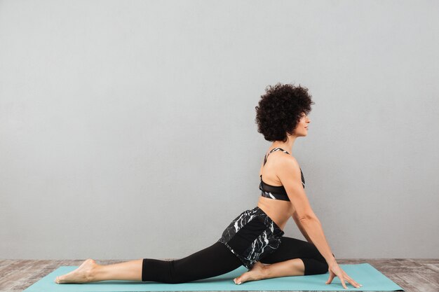 Femme de fitness assez bouclée faire des exercices de yoga sport