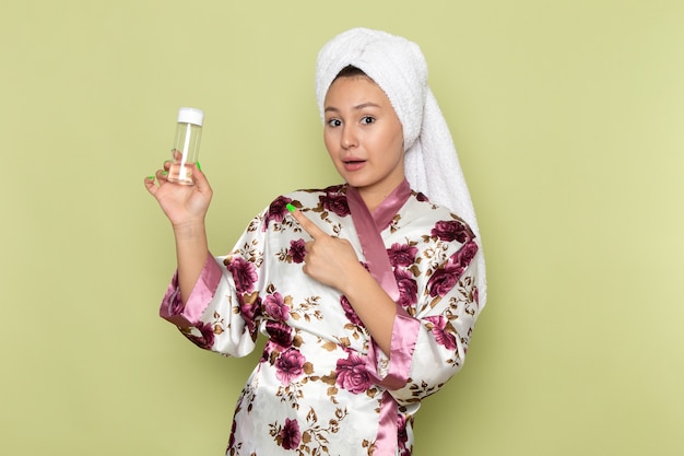 Femme en fleur pourpre peignoir conçu tenant un flacon de maquillage