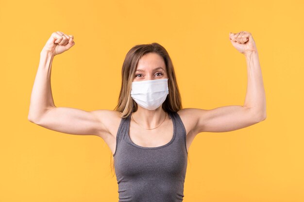 Photo gratuite femme forte avec masque médical montrant ses muscles