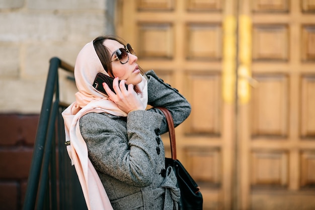 Femme avec un foulard rose parlant au téléphone