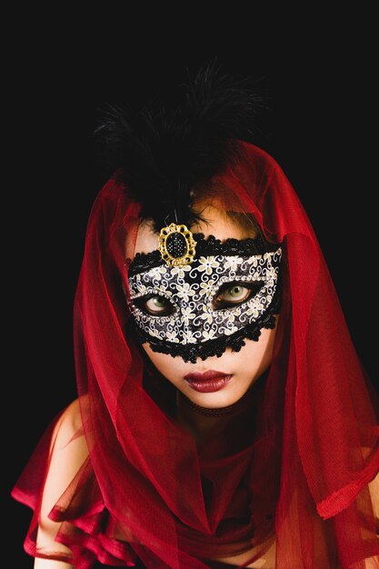 Femme avec un foulard rouge sur la tête et un masque vénitien