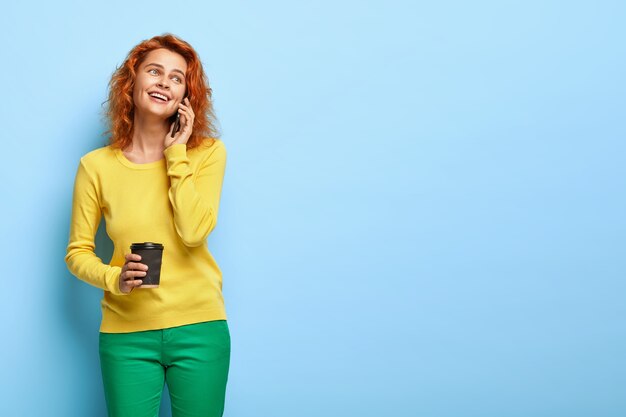 Une femme foxy aux yeux bleus heureux appelle son petit ami sur téléphone mobile, exprime des émotions positives