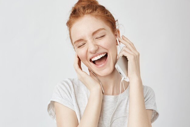Femme foxy joyeuse réjouissant écouter de la musique dans les écouteurs en souriant.