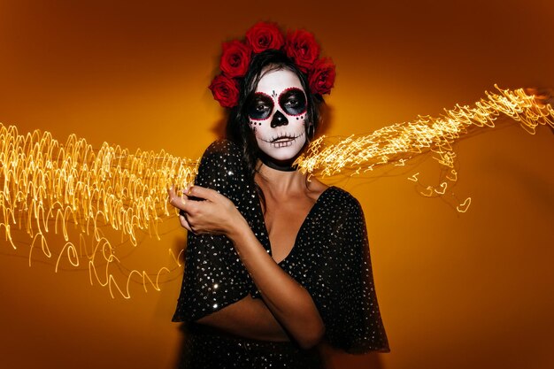 Une femme fragile en robe à pois regarde avec arrogance la caméra tout en se posant à la fête d'Halloween