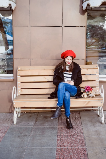 Femme française dans un béret rouge sur un banc de rue