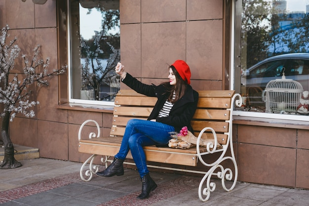 Femme française dans un béret rouge sur un banc de rue