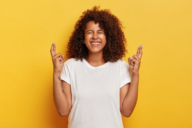 Femme frisée positive croise les doigts