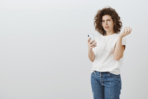 Une femme frustrée et confuse réagit à un message étrange sur un téléphone portable