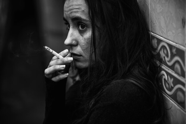Femme fumant la cigarette seule en niveaux de gris
