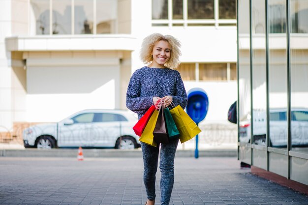 Femme gaie marchant avec des sacs