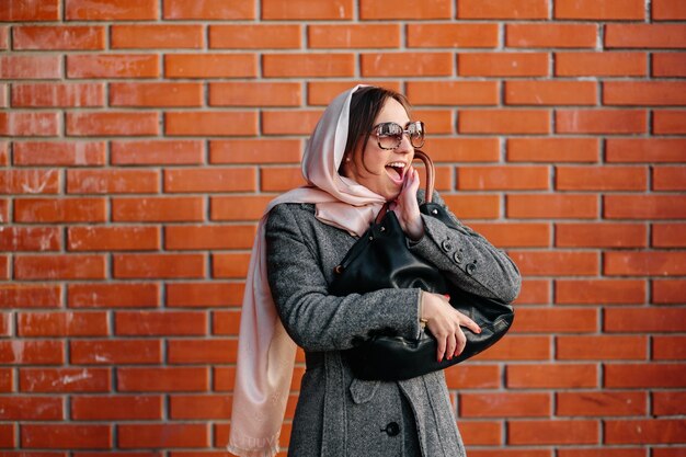 femme gaie avec mur de briques de fond