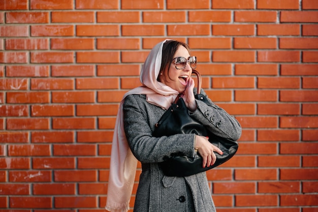 femme gaie avec mur de briques de fond