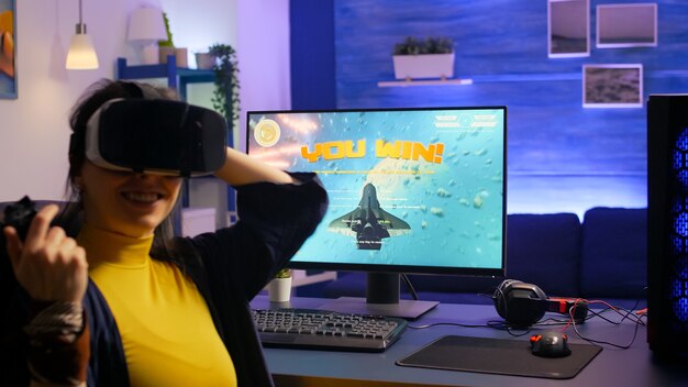 Femme gamer remportant des jeux vidéo de tir spatial tout en portant un casque vr dans un studio de jeu