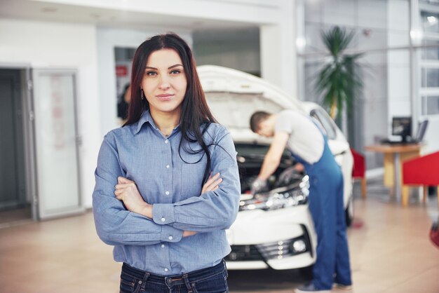 Femme, garage, voiture, obtenir, mécanique, service Le mécanicien travaille sous le capot de la voiture