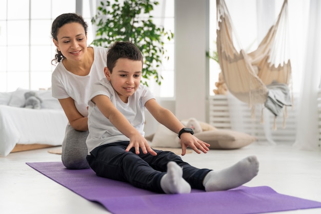 Femme et garçon sur tapis de yoga plein coup