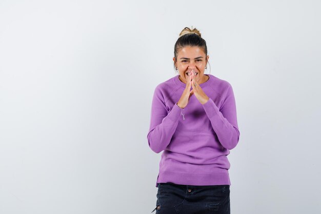 Femme gardant les mains en geste de prière en blouse de laine et à la joyeuse