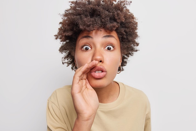 Photo gratuite une femme garde la main près de la bouche chuchote des informations secrètes habillées avec désinvolture répand des rumeurs isolées sur blanc dit des informations confidentielles