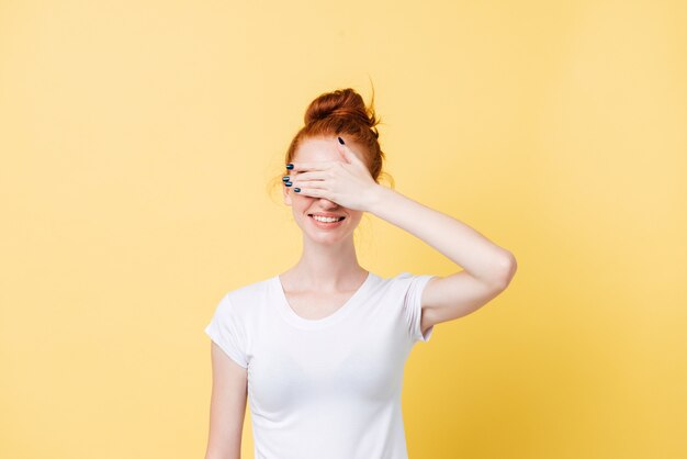 Femme gingembre souriante en t-shirt couvrant son visage